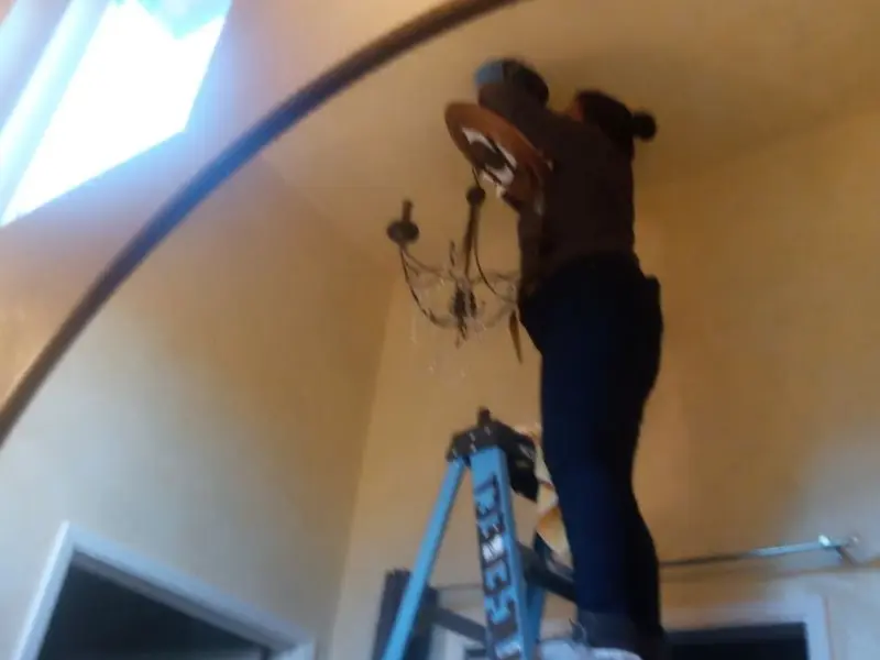 Electrician installing a chandelier in a Busti residence